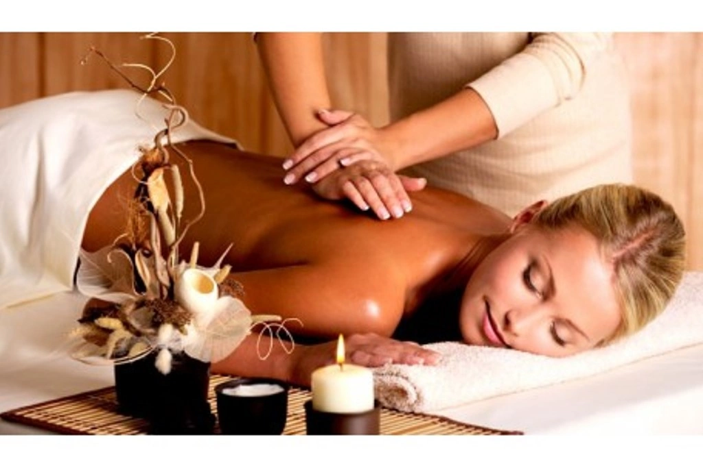 La imagen muestra a una mujer rubia acostada boca abajo recibiendo un masaje erótico para mejorar su salud mental.