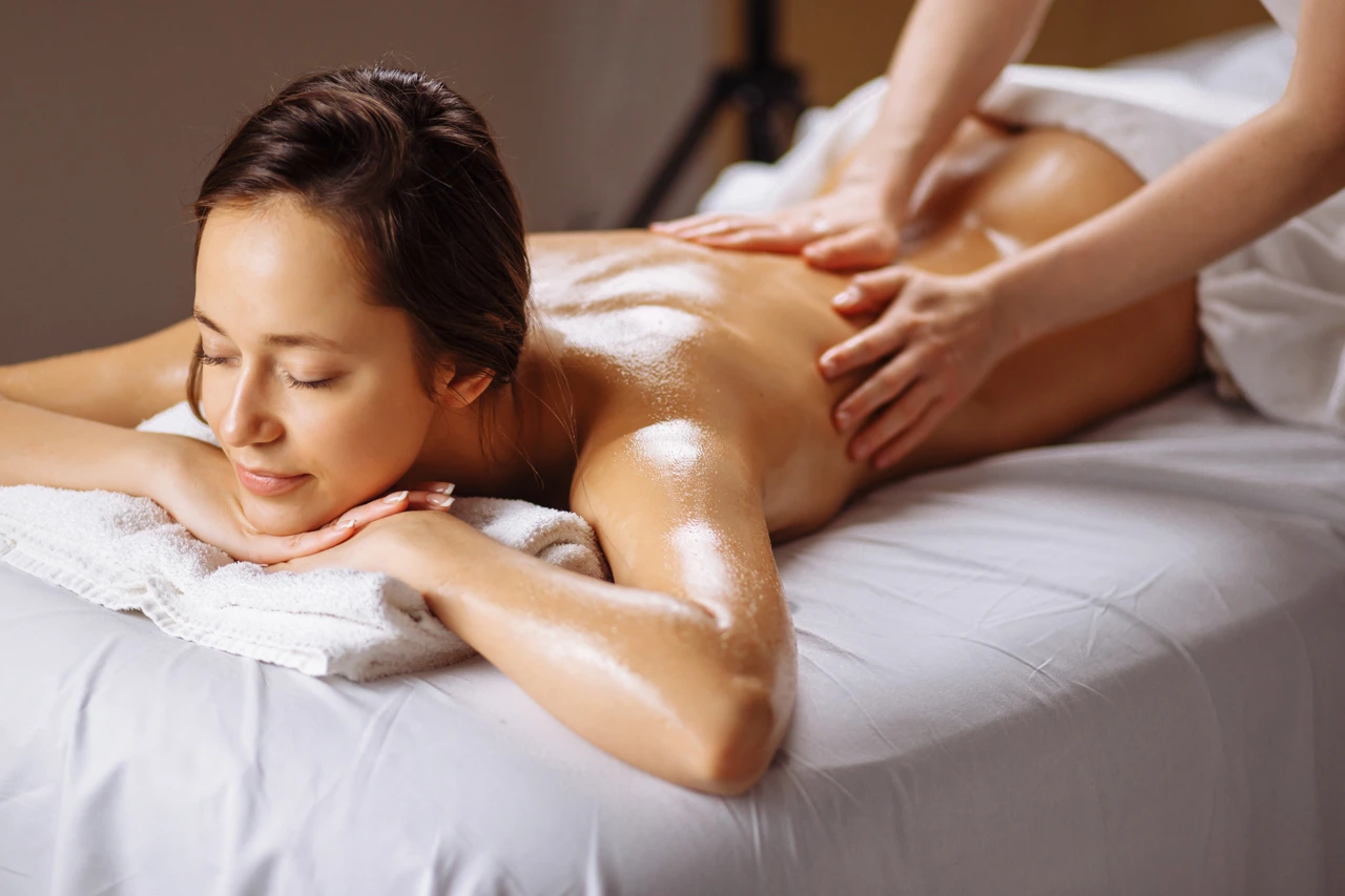 Mujer acotada boca abajo recibe un masaje tantrico muy popular en su espalda