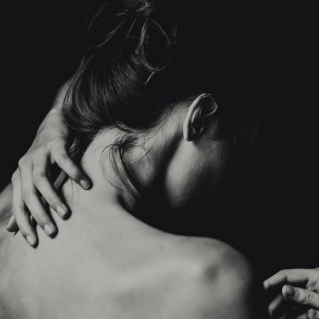 Una mujer de espaldas tocándose el cuello con una mano