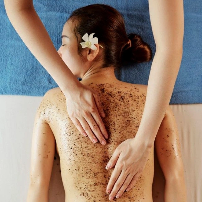 Mujer asiática con flor en su oreja y acostada, recibiendo masaje corporal