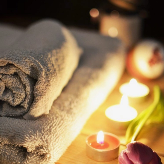 Toallas junto a velas aromáticas preparadas para la sesión de masajes masculinos a elección del cliente